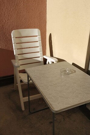 A small, enclosed outdoor seating area with a table and a chair. - Paradies 04 Zweibettzimmer, Dusche oder Bad, WC, 2-Bettwohnung Paradies 04 by Interhome (Arosa)