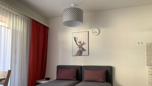 Een moderne slaapkamer met een grijze slaapbank, een wandklok en een hertenprint.