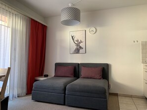 A modern bedroom with a grey sofa bed, a wall clock, and a deer artwork. - Paradies 04 Zweibettzimmer, Dusche oder Bad, WC, 2-Bettwohnung Paradies 04 by Interhome (Arosa)