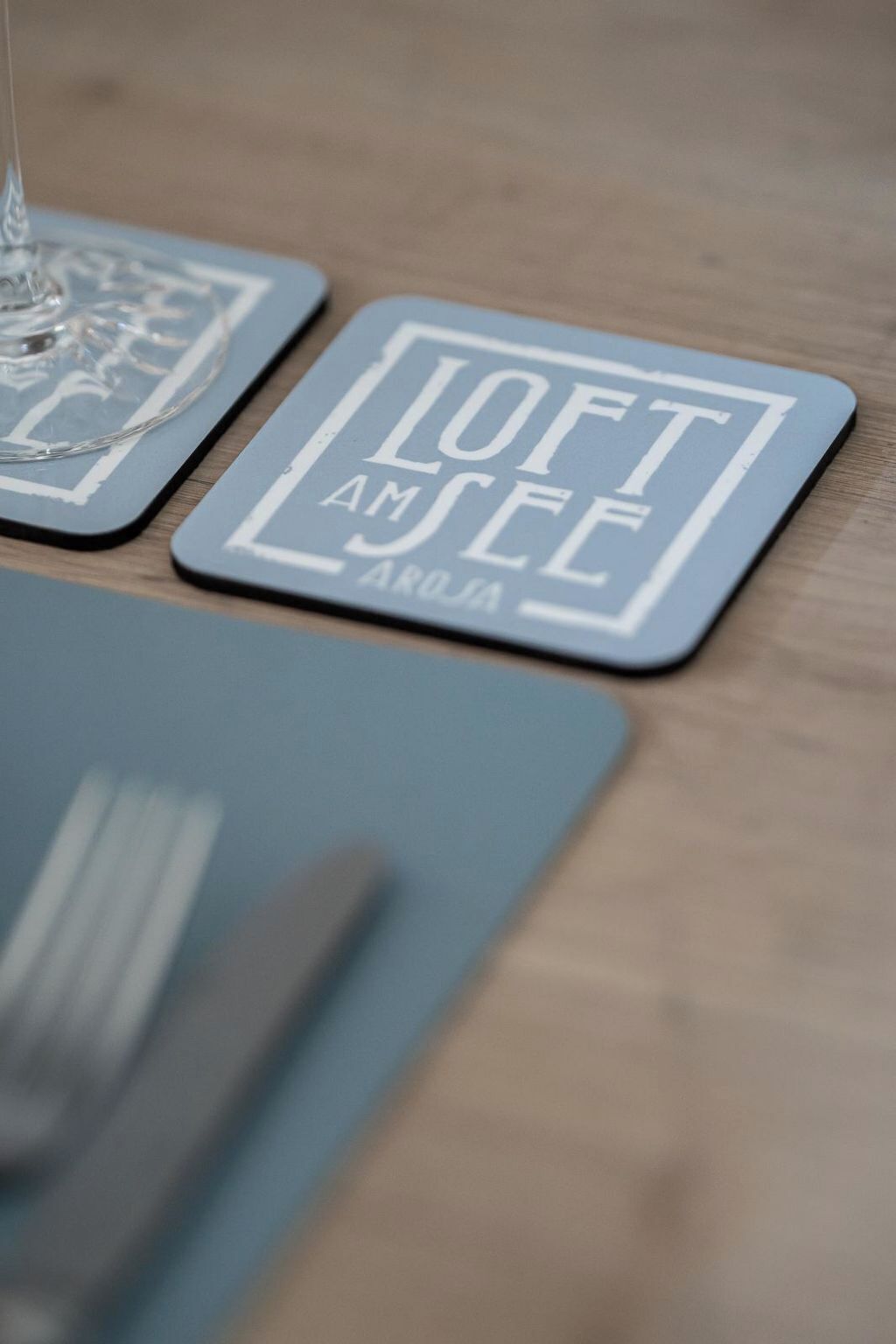Een close-up van een onderzetter met de tekst 'LOFT AM SEE' en 'AROJA' erop.