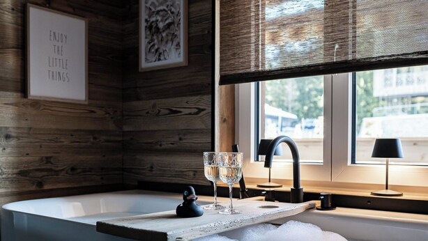 Eine moderne Küche mit einer Holzvertäfelung, einem Spülbecken mit Wasserhahn, zwei Gläsern und einem kleinen Dekoartikel auf der Arbeitsfläche.
