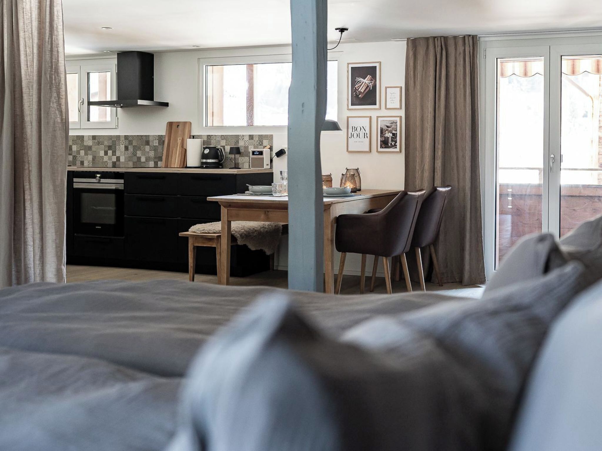 A modern kitchen with a dining area, a bed, and a view of the outdoors.