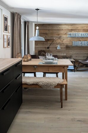 A dining area with a wooden table, benches, and a wall-mounted sign. - Loft am See Appartement/Fewo, Dusche und Bad, WC, Wohn-/Schlafraum LOFT AM SEE by Interhome (Arosa)