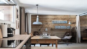 Eine moderne Küche mit Holzwänden, einem Esstisch, Stühlen und einer Pendelleuchte.