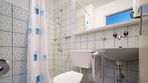 A bathroom with a toilet, a shower, and a sink.