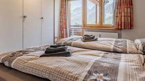 Quarto com cama, guarda-roupa e janela com cortinas.