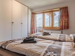 Ein Schlafzimmer mit einem Bett, einem Kleiderschrank und einem Fenster mit Vorhängen.