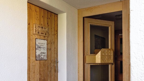 Uma porta de madeira com uma placa que diz 'SKIRAUM' e outra placa com texto em língua estrangeira.