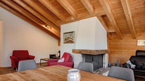 Interior em madeira com teto alto, lareira e disposição de assentos.