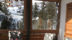 Ett träbord och stolar med blommigt tyg klätt på sitsarna, i ett ljust rum med stora fönster.