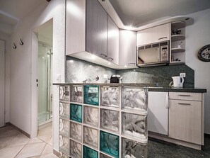 A modern kitchen with a built-in microwave, a coffee maker, and a clock on the wall. - Paradies 045 Appartement/Fewo, Dusche, WC, 2-Bettwohnung 2-Bettwohnung by Interhome (Arosa)