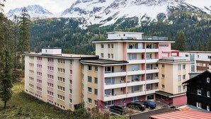 Ett hotell med flera våningar, en central innergård, en parkeringsplats och en imponerande bergsutsikt.