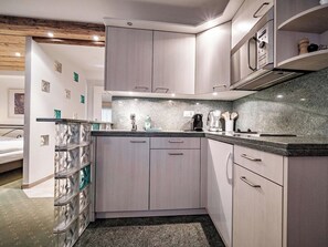 Eine moderne Küche mit grauen Schränken, einer Granit-Arbeitsplatte und einem eingebauten Backofen.