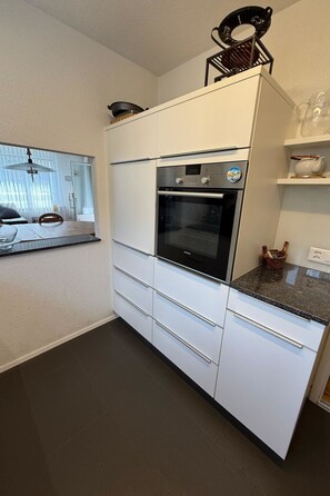Une cuisine moderne avec des meubles blancs, un four encastré et un plan de travail.