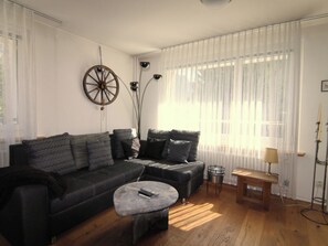 A modern living room with a dark-colored sofa, a round coffee table, and a lamp on a side table. - Casa dUval by Arosa Holiday Appartement/Fewo, Dusche, WC, 6-Bettwohnung by Interhome (Arosa)