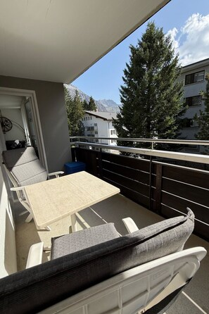 A balcony with a table and chairs, a view of a mountain, and a building in the background. - Casa dUval by Arosa Holiday Appartement/Fewo, Dusche, WC, 6-Bettwohnung by Interhome (Arosa)
