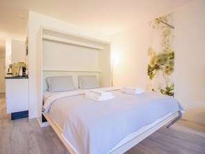 A modern bedroom with a bed, pillows, a bedside table, and a wall-mounted shelf. - Rothornblick 6 Appartement/Fewo, Bad, WC, 4-Bettwohnung Rothornblick 6 by Interhome (Arosa)