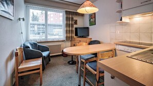 Een gezellig compact verblijf met een kitchenette, een eethoek en een zithoek met een bank en stoelen.