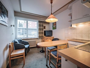 A compact living space with a kitchenette, a dining area, and a seating area with a sofa and chairs. - Paradies 002 Appartement/Fewo,  , 3-Bettwohnung 3-Bettwohnung by Interhome (Arosa)