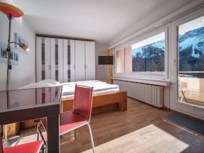 A bedroom with a bed, a desk, a chair, a TV, and a window with a mountain view. - Paradies 606 Appartement/Fewo, Bad, WC, 2-Bettwohnung by Interhome (Arosa)