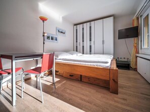 A bedroom with a wooden bed, a desk with a chair, a TV, and a wardrobe. - Paradies 606 Appartement/Fewo, Bad, WC, 2-Bettwohnung by Interhome (Arosa)