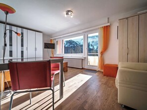 A modern living room with a wooden floor, a red chair, a white sofa, a TV, and a window with a view of mountains. - Paradies 606 Appartement/Fewo, Bad, WC, 2-Bettwohnung by Interhome (Arosa)