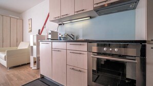 Una cocina moderna con horno empotrado y microondas, armarios de madera y encimera azul claro.