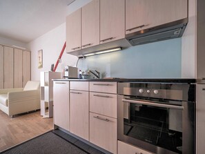 A modern kitchen with a built-in oven and a microwave, wooden cabinets, and a light blue countertop. - Paradies 606 Appartement/Fewo, Bad, WC, 2-Bettwohnung by Interhome (Arosa)