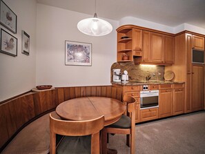 A kitchen with wooden cabinets, a round dining table, and a coffee maker. - Paradies 506 Appartement/Fewo,  , 2-Bettwohnung 2-Bettwohnung by Interhome (Arosa)
