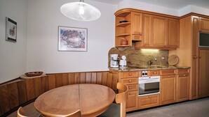 Una cocina con armarios de madera, horno empotrado y una mesa redonda con sillas.