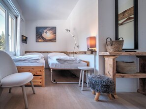 Ein kleiner, gemütlicher Raum mit zwei Betten, einem Schreibtisch, einem Stuhl, einer Lampe und einem Bild an der Wand.