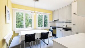 Una cocina con una mesa de comedor, sillas y un ventanal con vistas a zonas verdes.