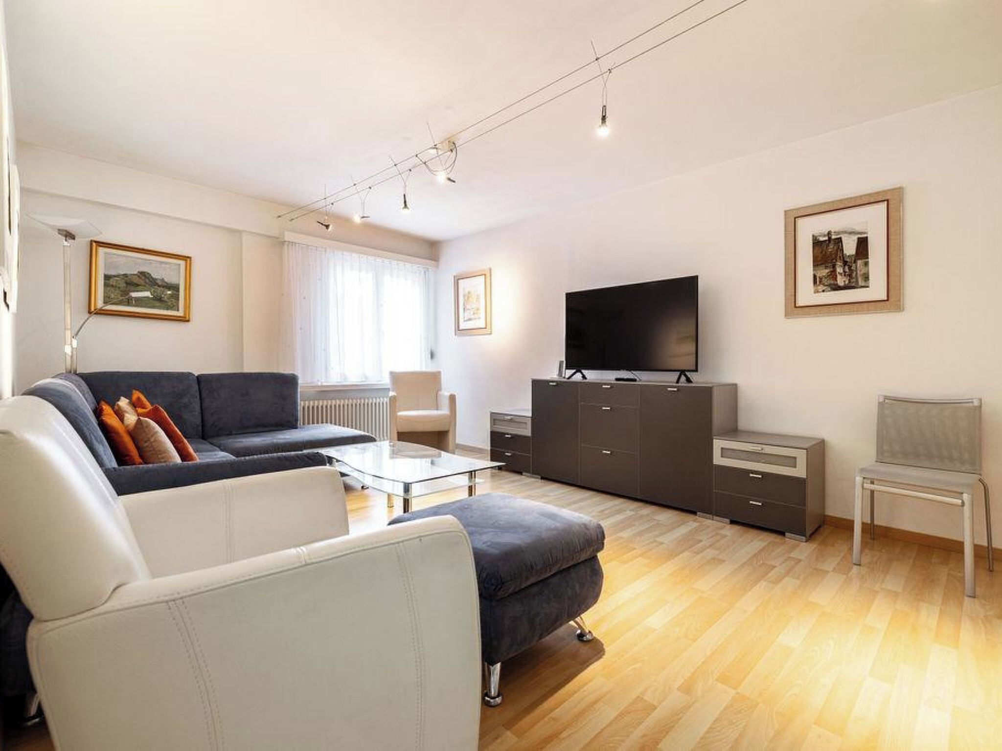 A modern living room with a sofa, coffee table, TV, and a cabinet.