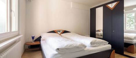 Une chambre à coucher moderne avec un lit, une table de chevet, un miroir et une fenêtre.
