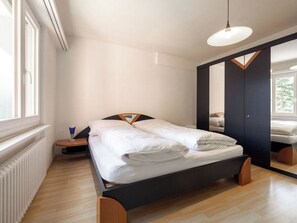 A modern bedroom with a bed, a bedside table, a mirror, and a window. - Paradies 021 Appartement/Fewo, Bad, WC, 4-Bettwohnung by Interhome (Arosa)