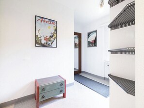 A hallway with a small wooden bench, a framed picture on the wall, and a metal shelf unit. - Paradies 021 Appartement/Fewo, Bad, WC, 4-Bettwohnung by Interhome (Arosa)