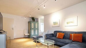 Una sala de estar moderna con un sofá, una mesa de centro de vidrio y un mueble.