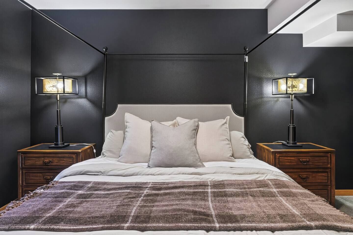 A bedroom with a bed, two bedside tables, and two floor lamps.