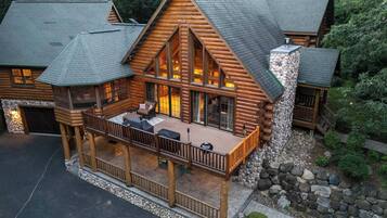 A log cabin with a deck, stone foundation, and a chimney.