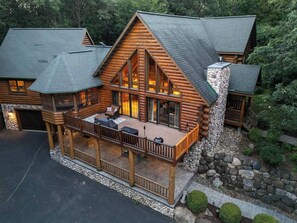 A log cabin with a deck, stone foundation, and a chimney.