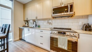 A modern kitchen with wooden cabinets, a stainless steel microwave, an oven, and a countertop with various kitchen items. - Rooftop Brews & Mtn Views: Central Seattle Gem (Seattle)