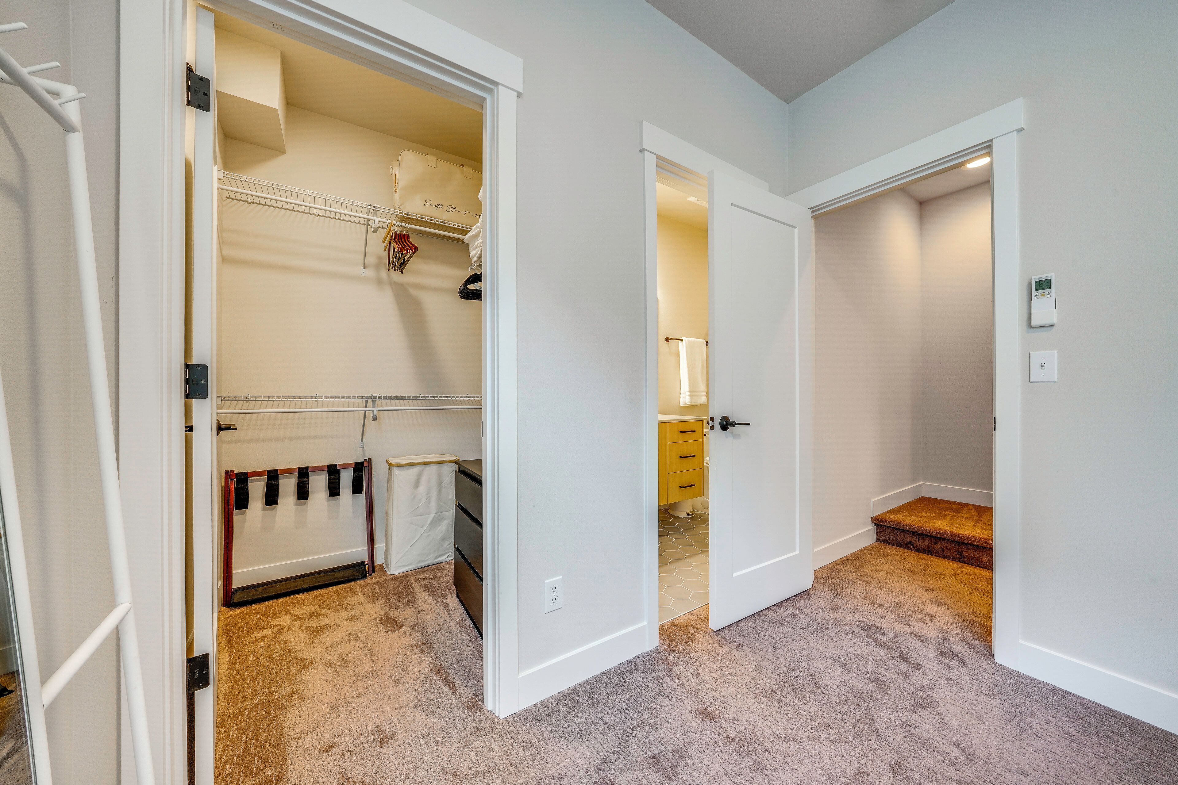 A room with a closet, a bathroom, and a door leading to another room.