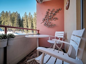 A balcony with a white table and chairs, a decorative wall piece, and a view of a snowy forest. - Paradies 301 Appartement/Fewo, Dusche oder Bad, WC, 4-Bettwohnung by Interhome (Arosa)