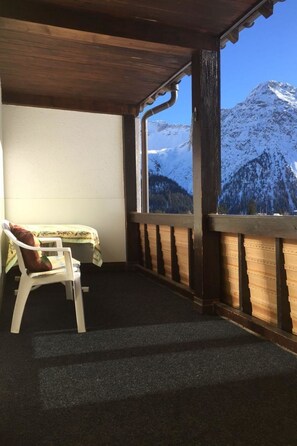A room with a view of snow-capped mountains, a wooden ceiling, and a single white chair with a cushion. - Sunnybank / 3. St. Appartement/Fewo, Dusche und Bad, WC, 10-Bettwohnung by Interhome (Arosa)