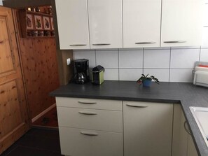 Une cuisine avec des meubles blancs, un plan de travail noir et une machine à café.