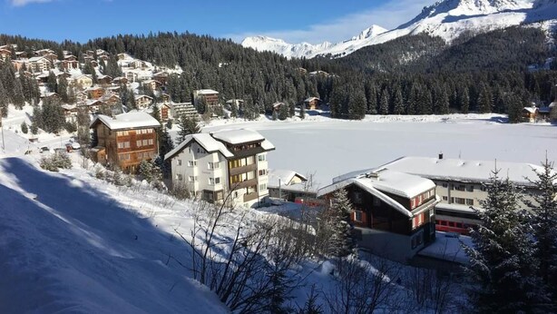Eine verschneite Bergstadt mit Gebäuden und einem zugefrorenen See.