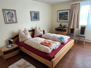 A bedroom with a wooden bed, two nightstands, a desk, a chair, and two paintings on the wall. - Sunnybank / 3. St. Appartement/Fewo, Dusche und Bad, WC, 10-Bettwohnung by Interhome (Arosa)