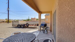 An outdoor patio with a table and chairs, a grill, and a trailer in the background. - Family Haven 4 Mi to Lake Havasu & London Bridge! (Lake Havasu City)