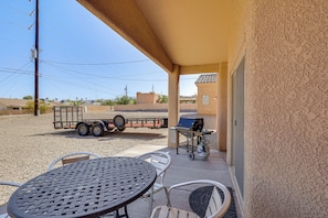 Eine Terrasse im Freien mit Tisch, Stühlen, einem Grill und einem Wohnwagen im Hintergrund.
