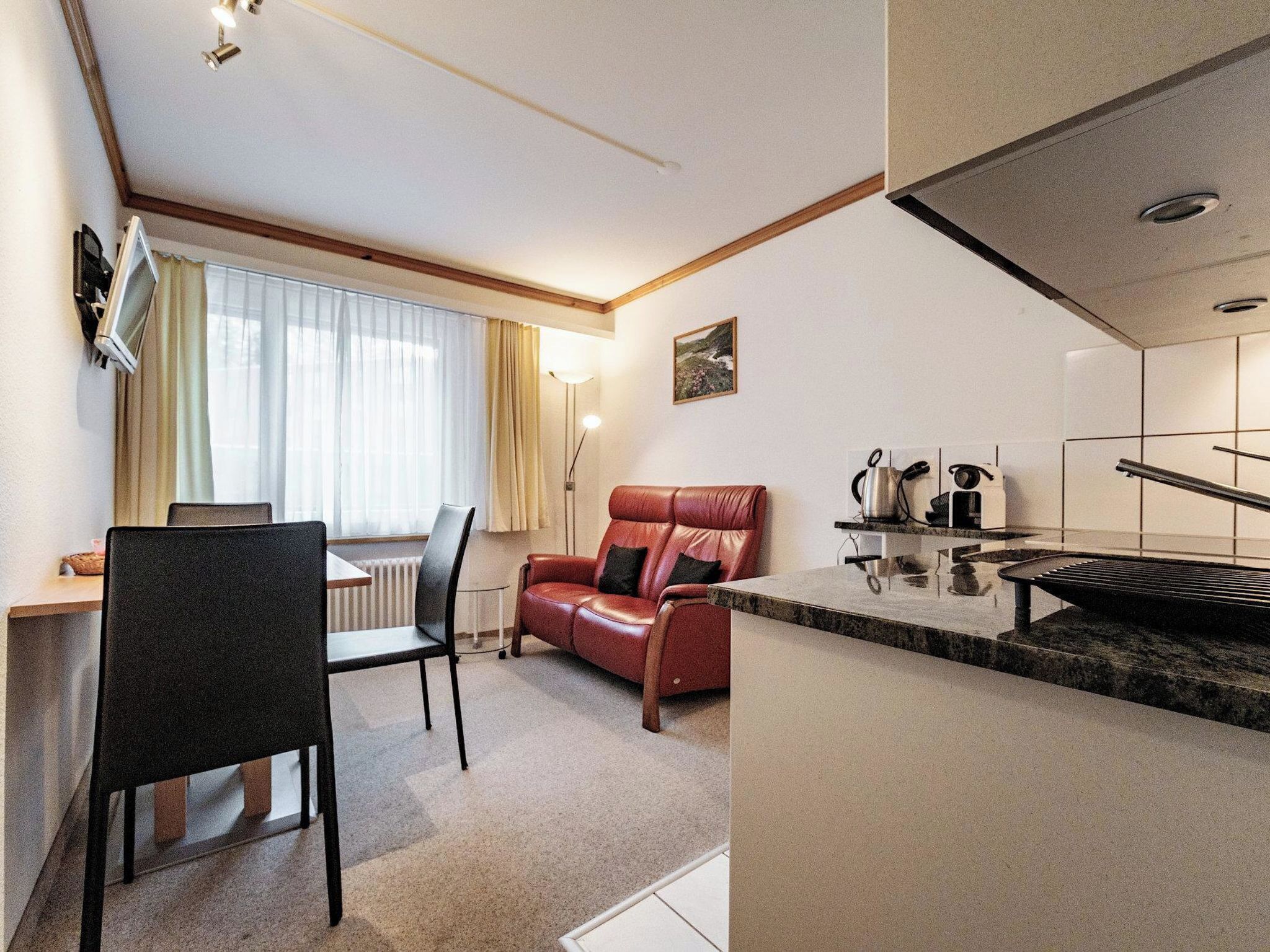 A compact living space with a kitchenette, a dining area with a table and chairs, and a seating area with a sofa.